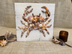 a crab made out of seashells sits next to a candle