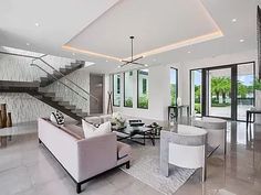 a living room filled with furniture and lots of windows next to a stair case that leads up to the second floor