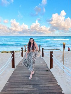 a woman standing on a pier near the ocean