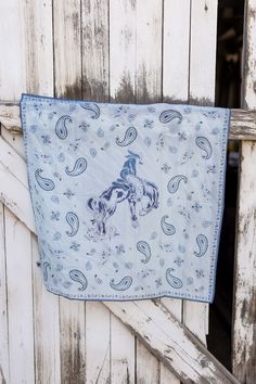 a blue bandana hanging on the side of a wooden fence with an image of a horse