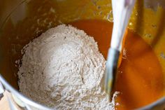 a mixing bowl filled with flour and orange liquid