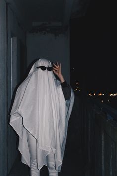 a person dressed in white and holding their hands up to the sky while standing on a balcony