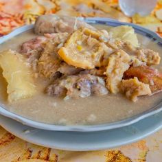 a white plate topped with meat and potatoes covered in gravy on top of a table