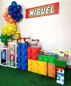 a room filled with toys and balloons on top of green carpeted flooring in front of a white wall