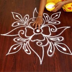 a woman is drawing on the floor with white chalk