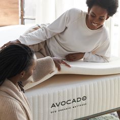 two women are sitting on an avocado mattress