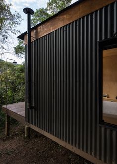 a black metal building with a bed in the corner and trees behind it on a hillside