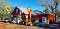 an old fashioned gas station sits on the side of a dirt road in front of trees