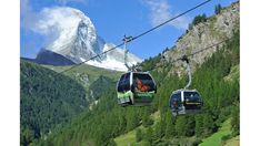 two gondolas with mountains in the background and snow capped mountain range behind them