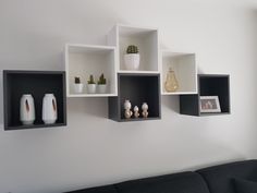 three black and white shelves on the wall with vases in them, one is empty