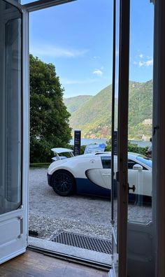 a bugatti parked in front of a glass door with mountains in the background