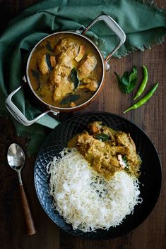 chicken curry and rice on a black plate with a green napkin next to it, along with a spoon