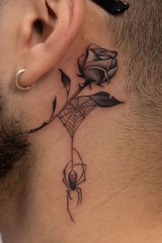 a man's neck with a spider and rose tattoo on the back of his neck