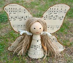 a wooden angel with musical notes on it's wings, sitting in the grass