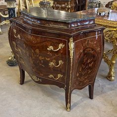 an ornately decorated chest of drawers sits in a room filled with chairs and tables