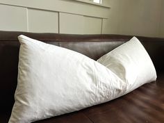 a white pillow sitting on top of a brown leather couch