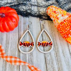 a pair of fish earrings sitting on top of a wooden table next to a pumpkin