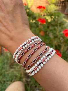 a woman's arm with three bracelets on it and flowers in the background