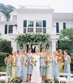 a group of women standing next to each other in front of a white house