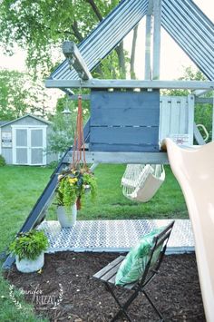 a backyard with a swing, chair and potted plants on the ground in front of it