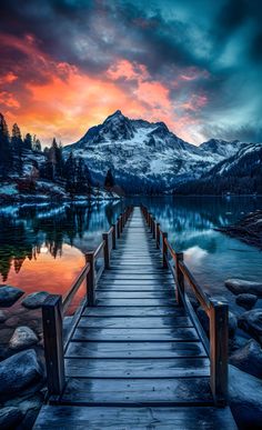 a wooden dock sitting on top of a lake under a cloudy sky with mountains in the background