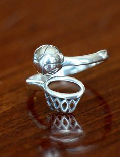 a silver ring sitting on top of a wooden table with a basketball hoop in it