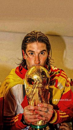 a man holding a soccer ball in his hand and wearing a red, yellow and white uniform