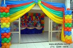 an entrance to a birthday party with balloons and streamers on the door, decorated in rainbow colors