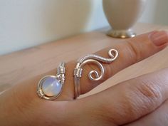 a woman's hand with two rings on it and a vase in the background