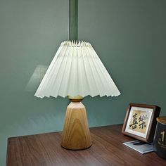 a lamp sitting on top of a wooden table next to a framed picture and an old book