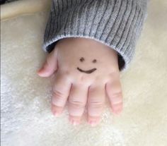 a small child's hand with a smiley face drawn on the middle of it