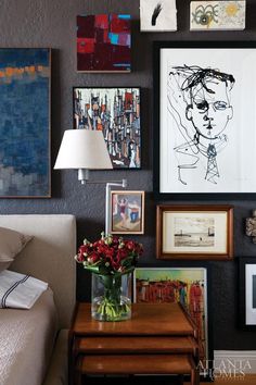 a living room filled with lots of pictures and paintings on the wall above a table