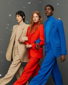 three models in bright colored outfits walking down the runway