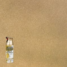 a bottle of spray paint sitting on top of a brown surface with gold flecks