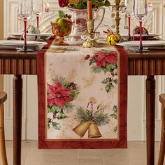 a christmas table runner with poinsettis and bells on it, sitting at a dining room table