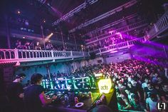 a large group of people at a concert with djs in front of the stage