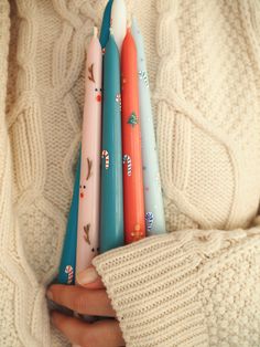 a person holding four different colored toothbrushes in their hands and wearing sweaters