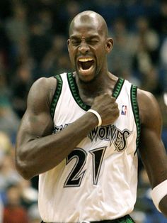 a male basketball player with his fist up and mouth wide open in front of the crowd