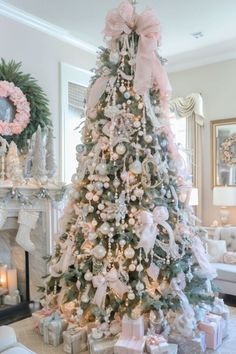 a decorated christmas tree in a living room with pink and white ornaments on the top