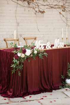 the table is set up with candles and flowers for an elegant wedding reception in front of a brick wall