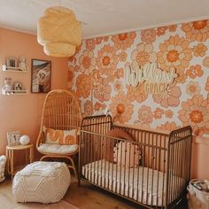 a baby's room with an orange flower wallpaper and a wicker crib