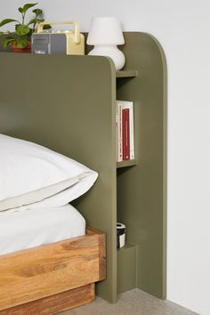 a bed with a book shelf next to it and a lamp on the wall behind it