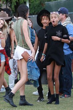 a group of people standing on top of a grass covered field next to each other