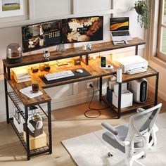 a computer desk with two computers on it and a chair in front of the window