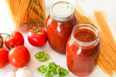 tomatoes, pasta and garlic are on the table next to some jars with tomato sauce