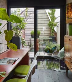 a living room filled with furniture and lots of green plants on top of wooden flooring