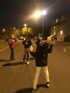 three people standing in the middle of a street at night with one person taking a selfie