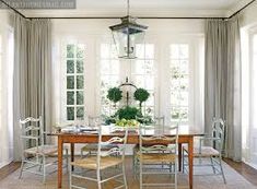 a dining room table with chairs and a lantern hanging from the ceiling over it's windows