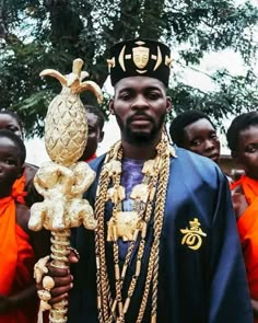 a man wearing an elaborately decorated crown and holding a golden object in front of other people