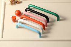 several different colored handles and knobs on a white surface with an orange object in the background